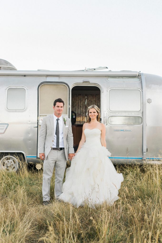 couple posing outside vintage airstream rustic barn wedding