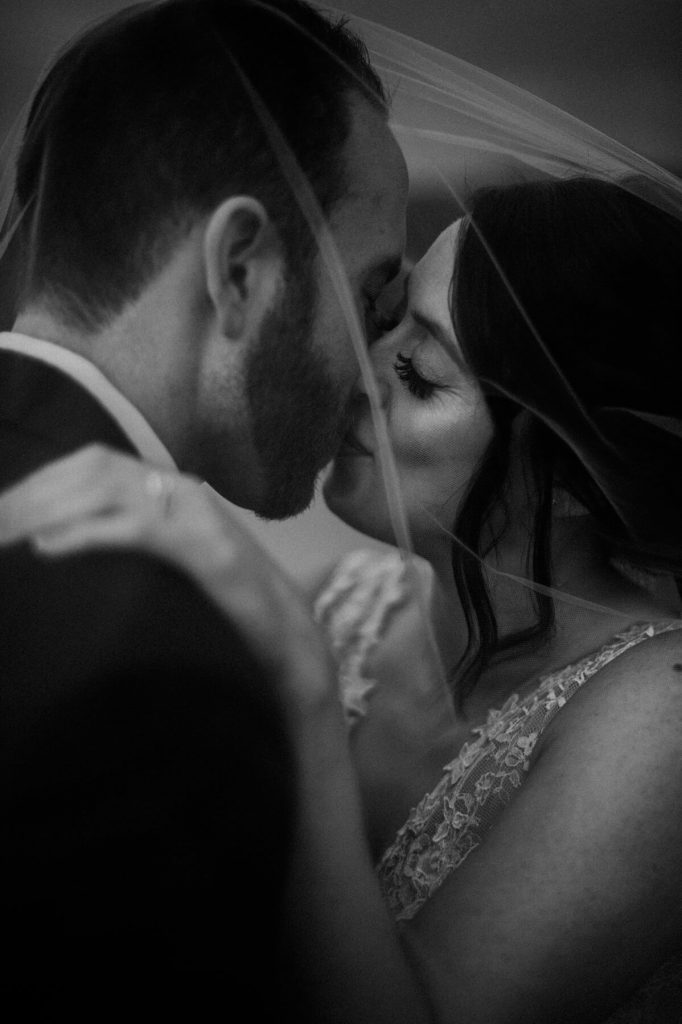 groom and bride kiss under veil 