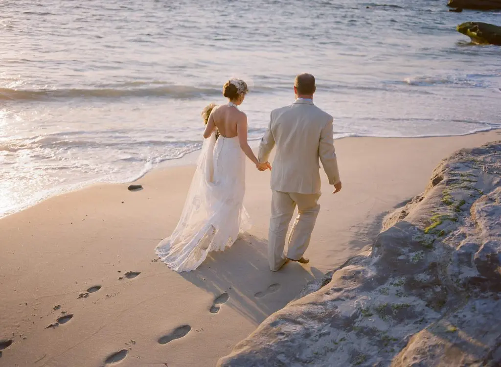 couple walk hand in hand on sand windansea beach intimate wedding