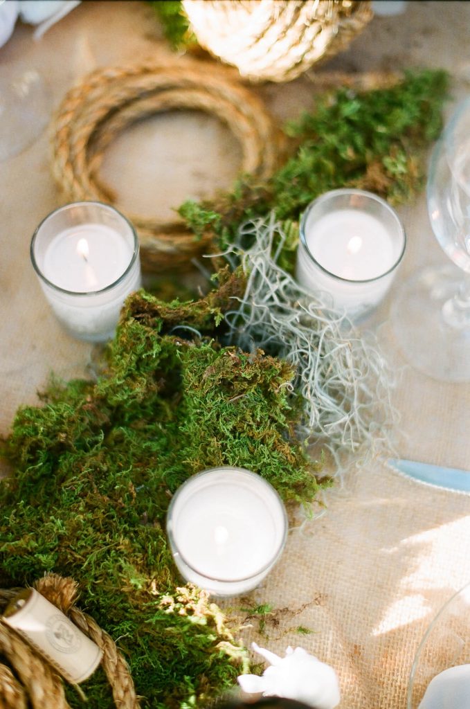 votive candles and green moss with ropes for sailing themed centerpiece