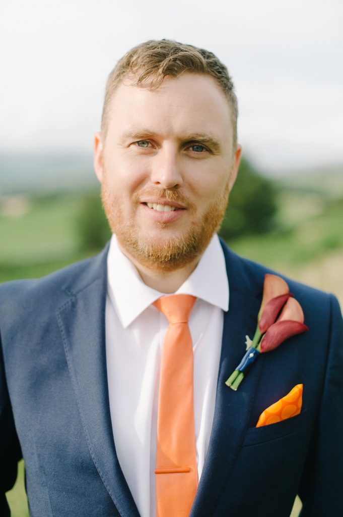 groom wearing blue suit and orange tie portrait kendal uk lake district wedding