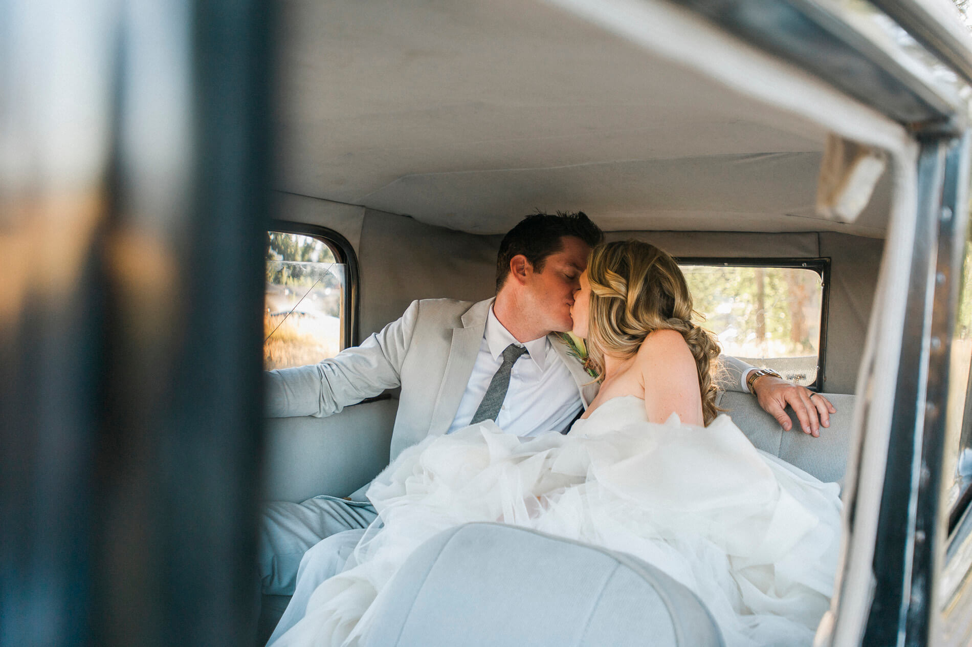 bride and groom kissing in back of vintage car