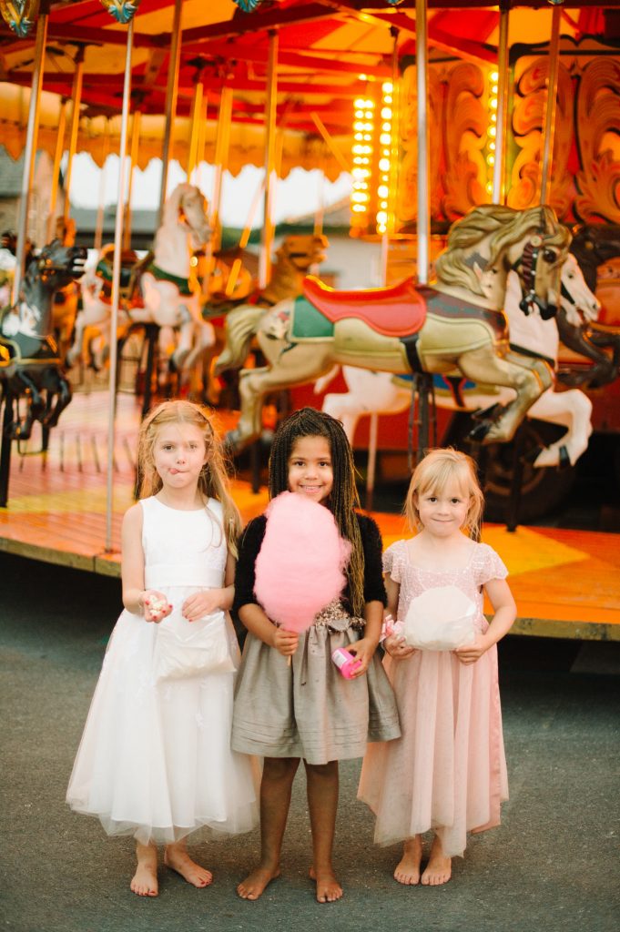 young girls holding cotton candy near carousel carnival themed wedding reception lake district england