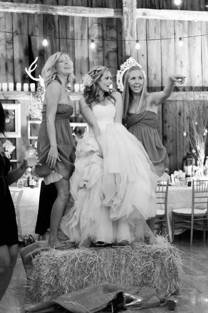 bride and bridesmaids dancing on bale of hay rustic barn wedding lake almanor