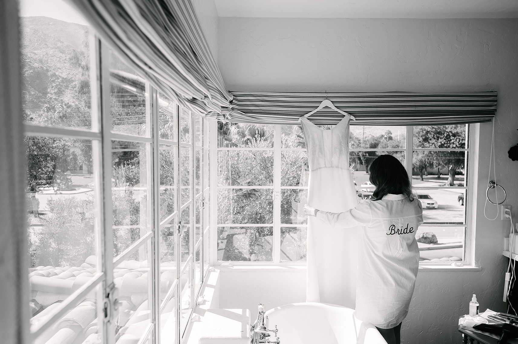 bride admires wedding gown hanging in bathroom before colony palms hotel wedding in palm springs