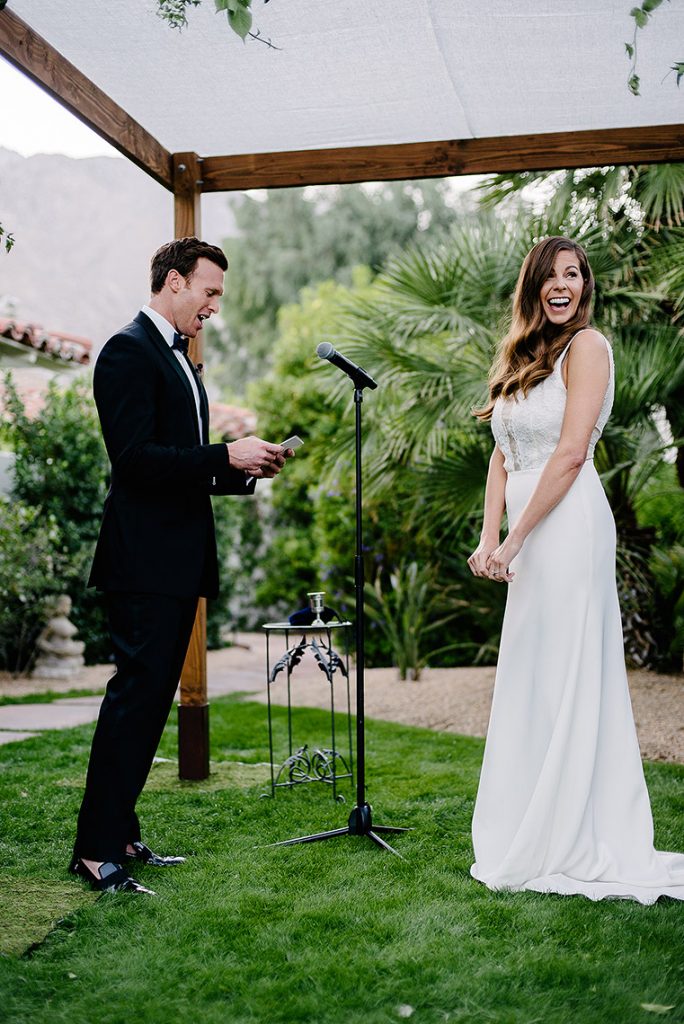 bride smiles as groom reads vows under chuppah colony palms hotel wedding