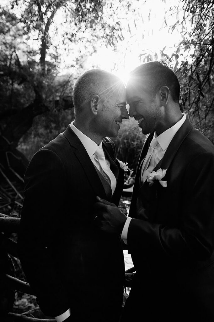 two grooms embracing sun flare calamigos ranch same sex wedding