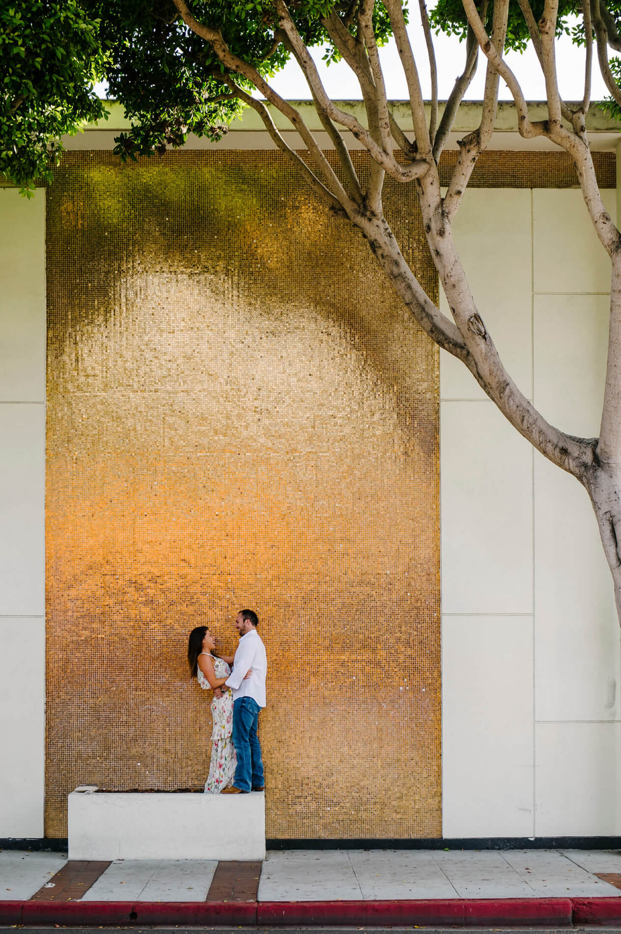 couple posing against gold wall downtown laguna beach engagement photo