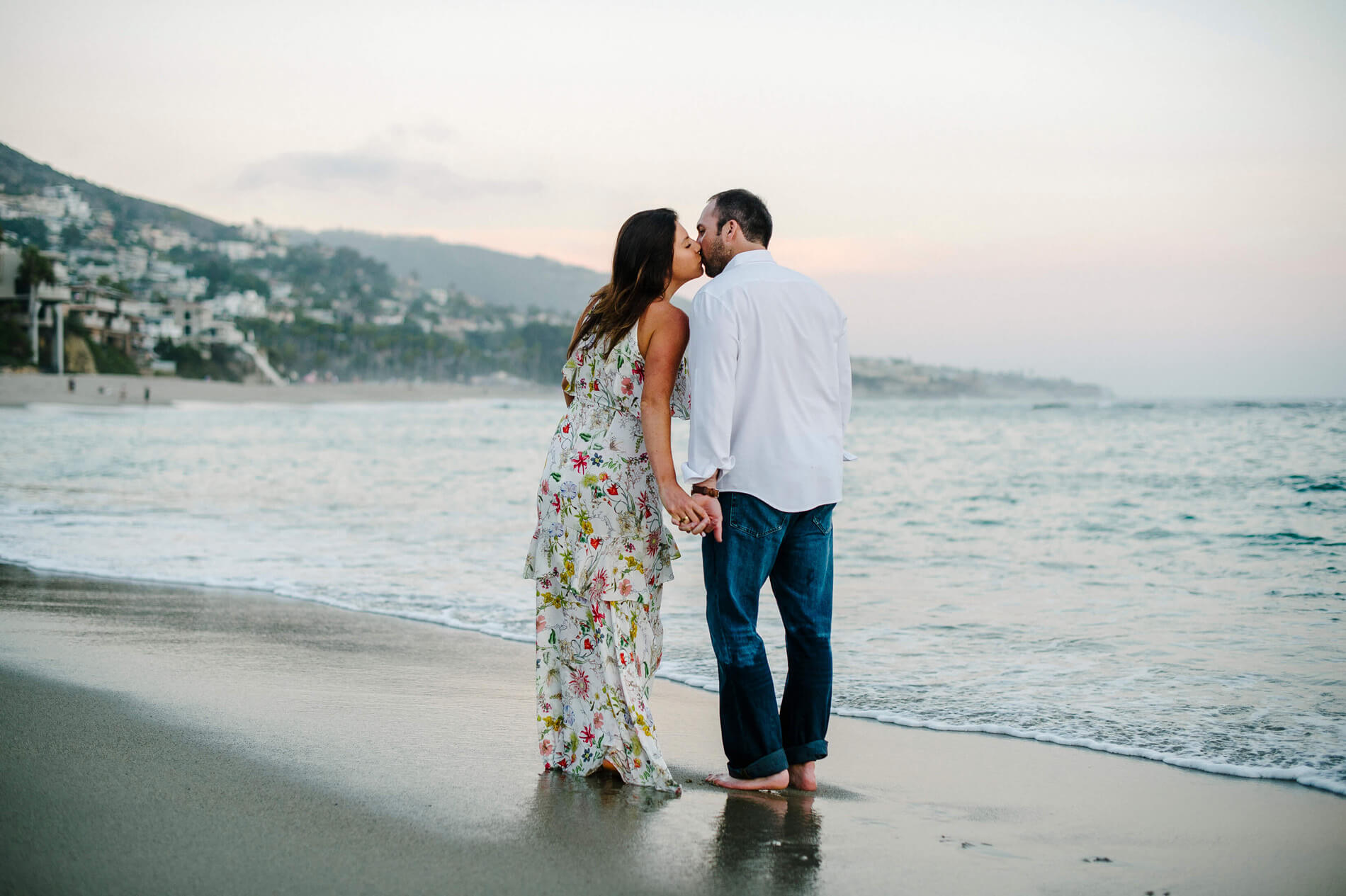 couple walking on beach kissing at dusk laguna beach engagement