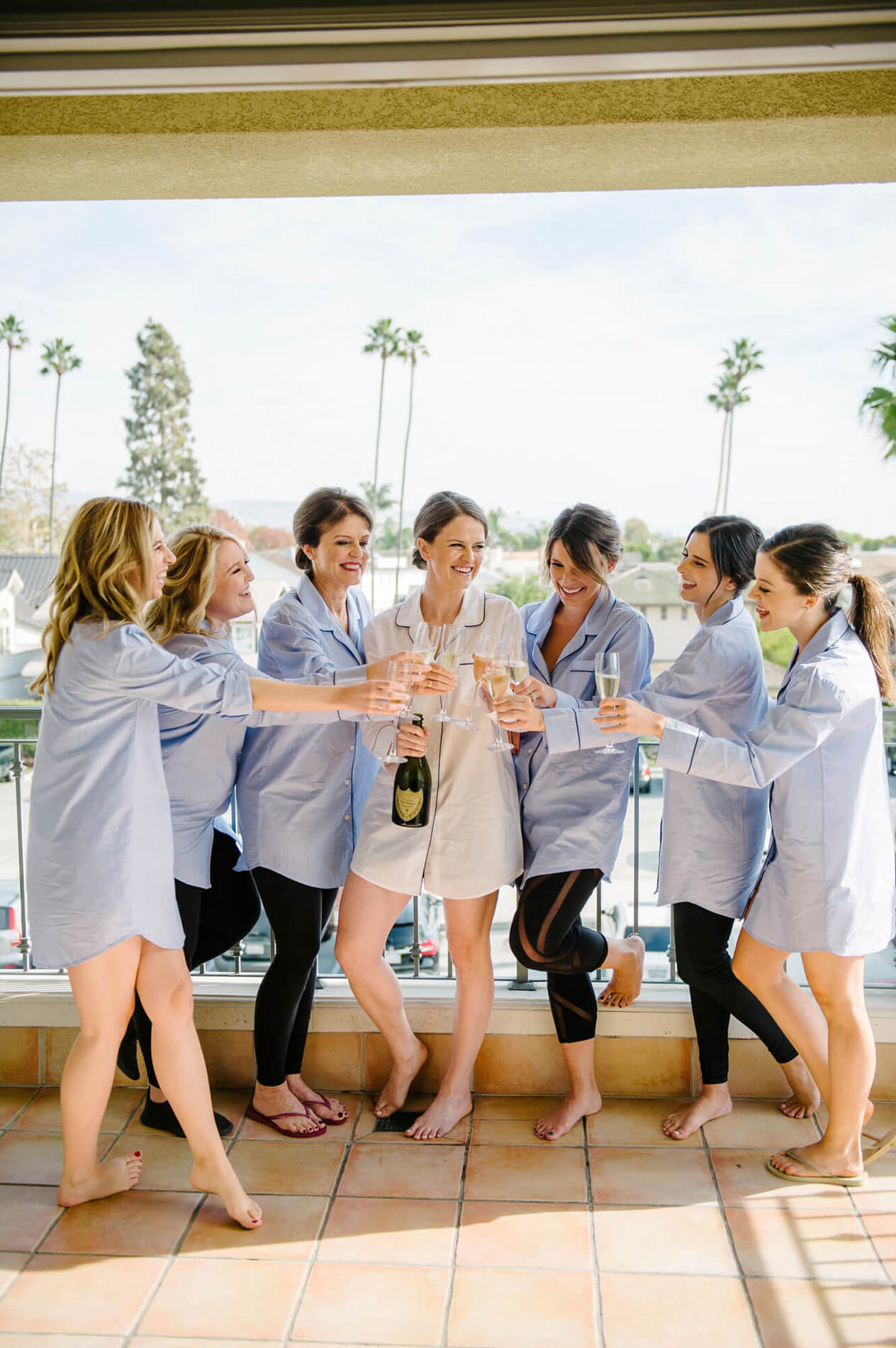 bride and bridesmaids wearing matching pajamas celebrate with champagne at bay club newport beach