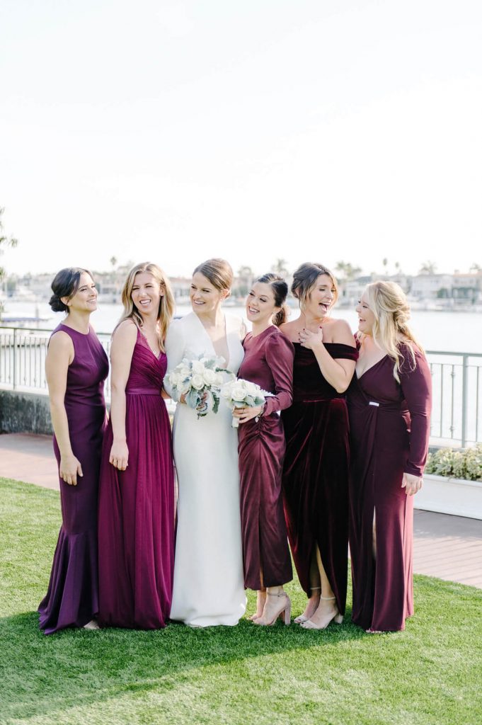 bride and bridesmaids wearing purple dresses pose at balboa bay club