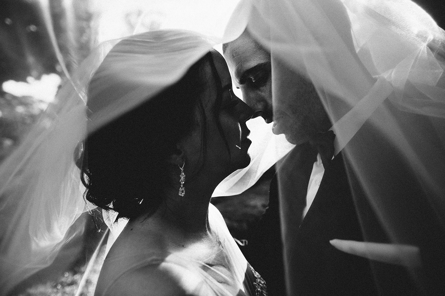 bride and groom kiss romantically under veil