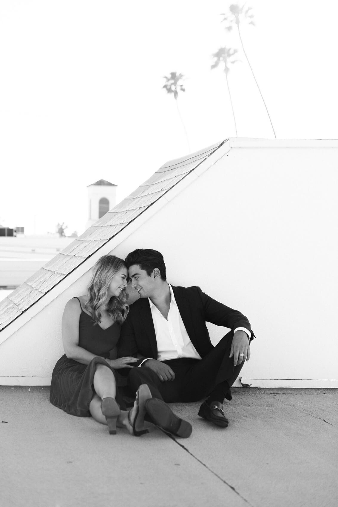 couple sit on rooftop downtown la jolla engagement shoot