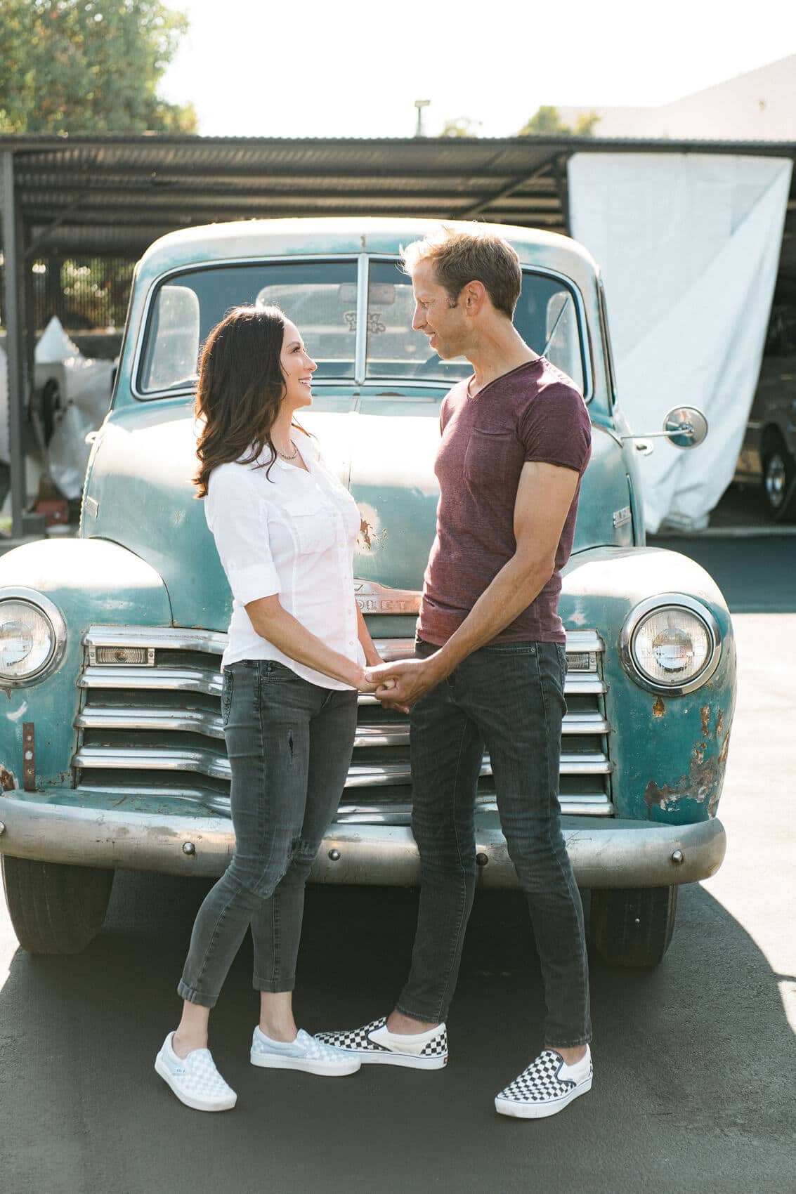 couple holding hands in front of blue vintage pickup truck industrial engagement photo