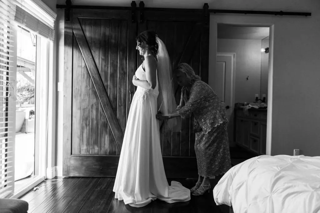 mother helping bride with dress before intimate wedding in oakhurst