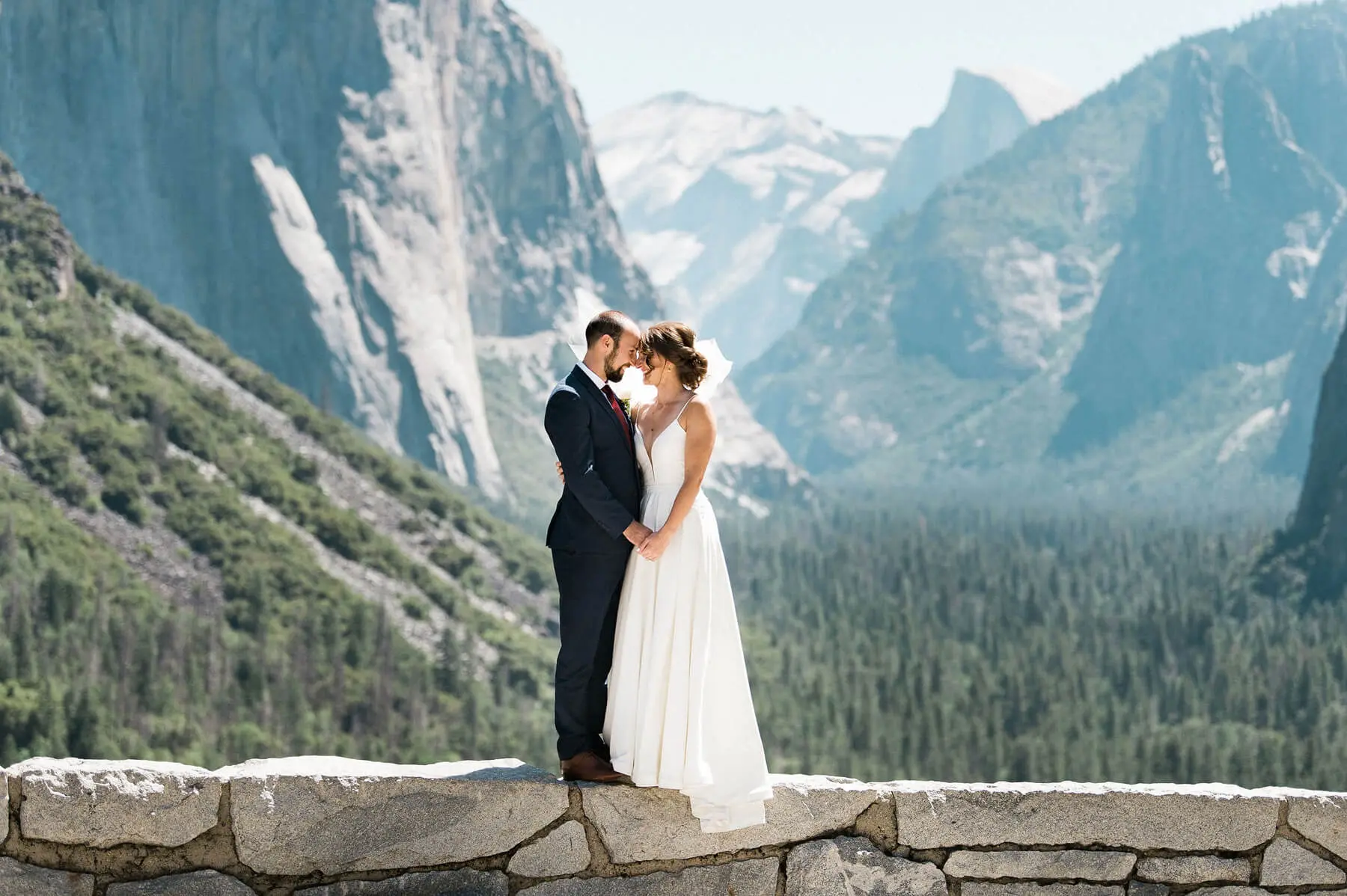 bride and groom posing on wall at tunnel view with halfdome and valley in background yosemite adventure elopement