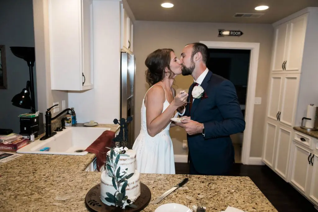 bride and groom kissing after cutting cake at intimate wedding reception at private residence in oakhurst california