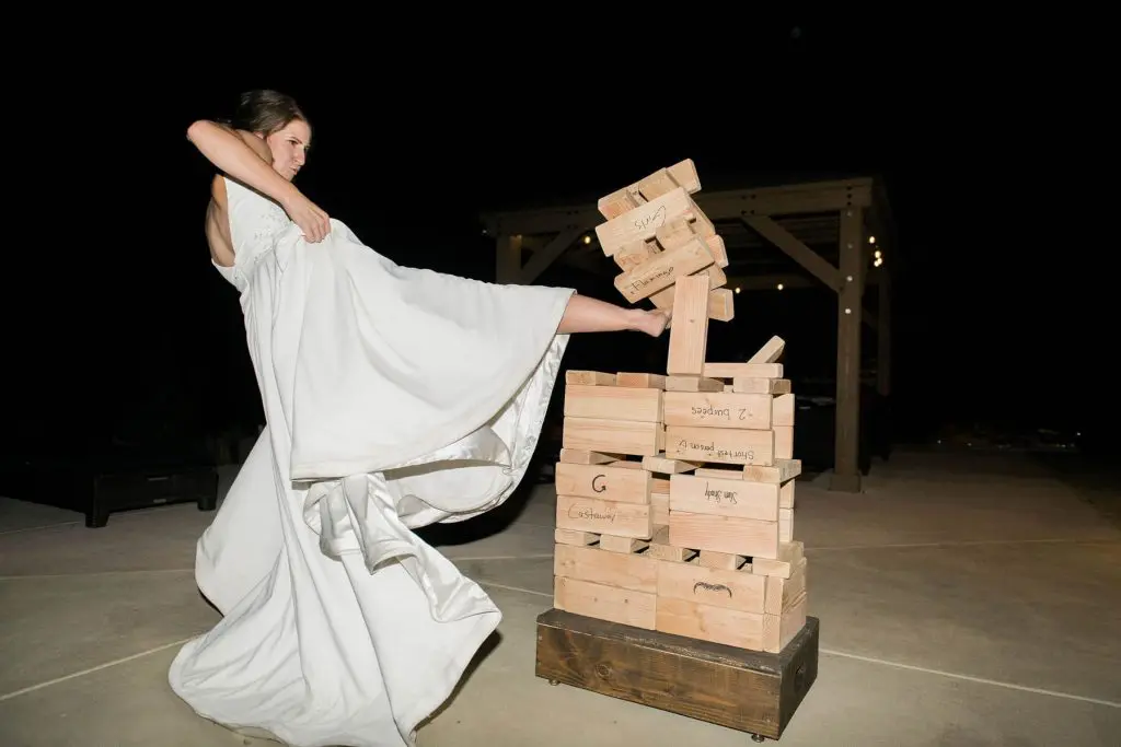 bride kicks over a life-sized jenga game intimate wedding reception oakhurst