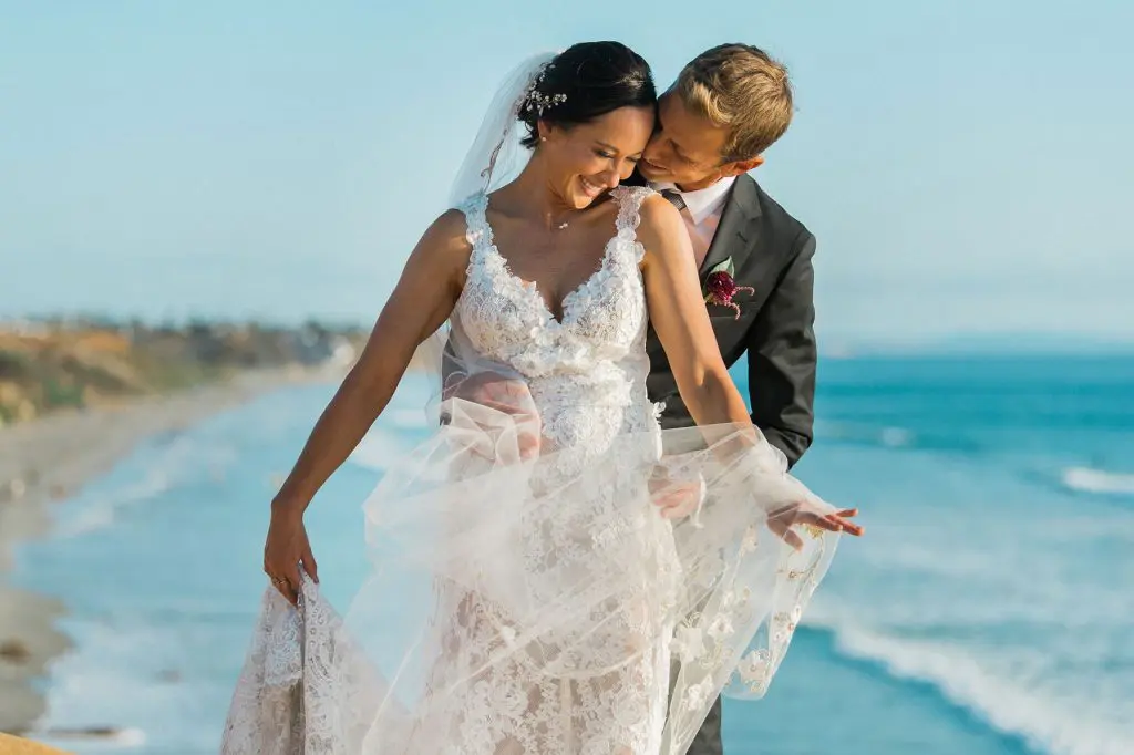 bride and groom embracing on cliff above ocean san diego wedding